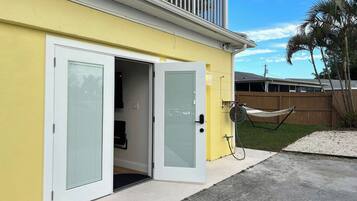 Un bâtiment jaune avec une porte blanche et un petit porche fermé.