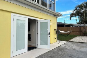 Un edificio amarillo con una puerta blanca y un pequeño porche cerrado.