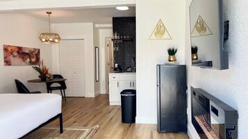 Una habitación de hotel moderna con cama, escritorio, comedor, cocina y sala de estar.