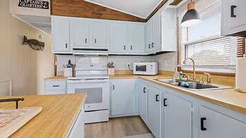 A kitchen with white cabinets, a microwave, a sink, and a wooden countertop.
