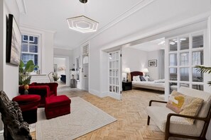 A spacious living room with a red sofa, a white armchair, and a herringbone-patterned floor. - Holland Park 5BR Sauna Garden Parking (London)