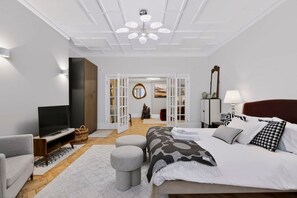 A modern bedroom with a bed, TV, and a walk-in closet. - Holland Park 5BR Sauna Garden Parking (London)