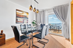 Un espace repas moderne avec une table en verre, des chaises noires et une vue sur la ville.