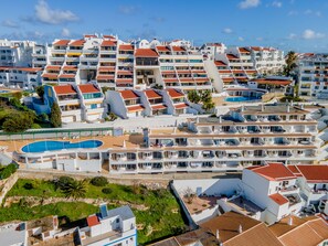 Um hotel à beira-mar com várias varandas, piscina e vista para o mar.