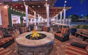 An outdoor patio area with a circular stone fire pit surrounded by cushioned seating. - Cozy 2-bedroom Apartment With Shared Pool in Orlando (Orlando)