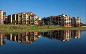 A multi-story hotel with a reflection in the water, featuring a flat roof and a symmetrical facade. - Cozy 2-bedroom Apartment With Shared Pool in Orlando (Orlando)