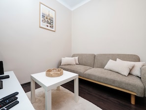 Sala de estar com sofá, mesinha e quadro na parede.