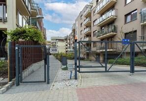 A gated residential area with apartment buildings, a clear sky, and a paved walkway. - Park Reduta Harmony Apartment (Kraków)