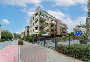 Een meerlaags woongebouw met balkons, een hekpoort en een heldere lucht.