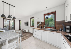 A modern kitchen with white cabinetry, a wooden countertop, and a large window. - Park Reduta Harmony Apartment (Kraków)