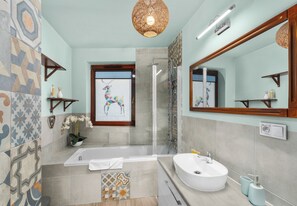 Een moderne badkamer met een bad, douche en wastafel.