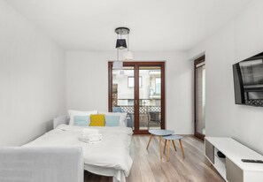 Een hotelkamer met een bed, een tafeltje, een televisie en een schuifdeur naar een balkon.