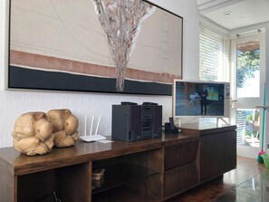 A modern living room with a large flat-screen TV, a wooden entertainment unit, and a unique abstract art piece above the TV. - Vrbo Property (Gramado)