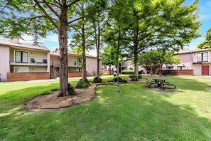 A residential area with multiple apartment buildings, a picnic table, and a well-maintained lawn. - The Modern Stay - Near Stadiums & DFW Airport (Addison)