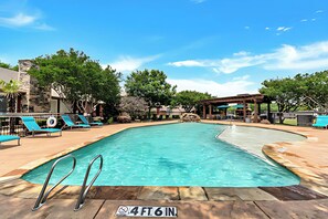A swimming pool with a 4 ft 6 in depth marker, surrounded by lounge chairs and a stone building. - The Modern Stay - Near Stadiums & DFW Airport (Addison)