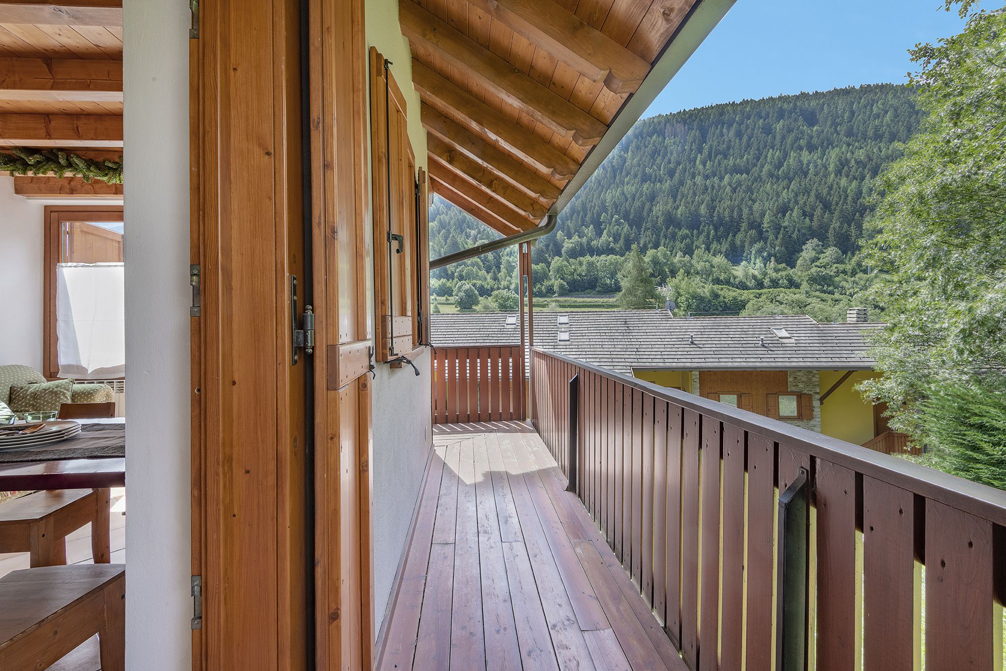 Un balcone in legno con vista su una montagna boscosa.