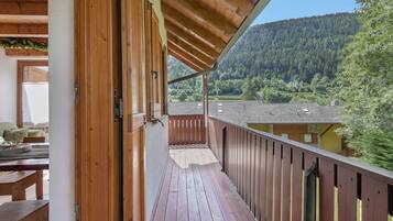 Un balcone in legno con vista su una montagna boscosa.