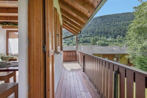 Un balcone in legno con vista su una montagna boscosa.