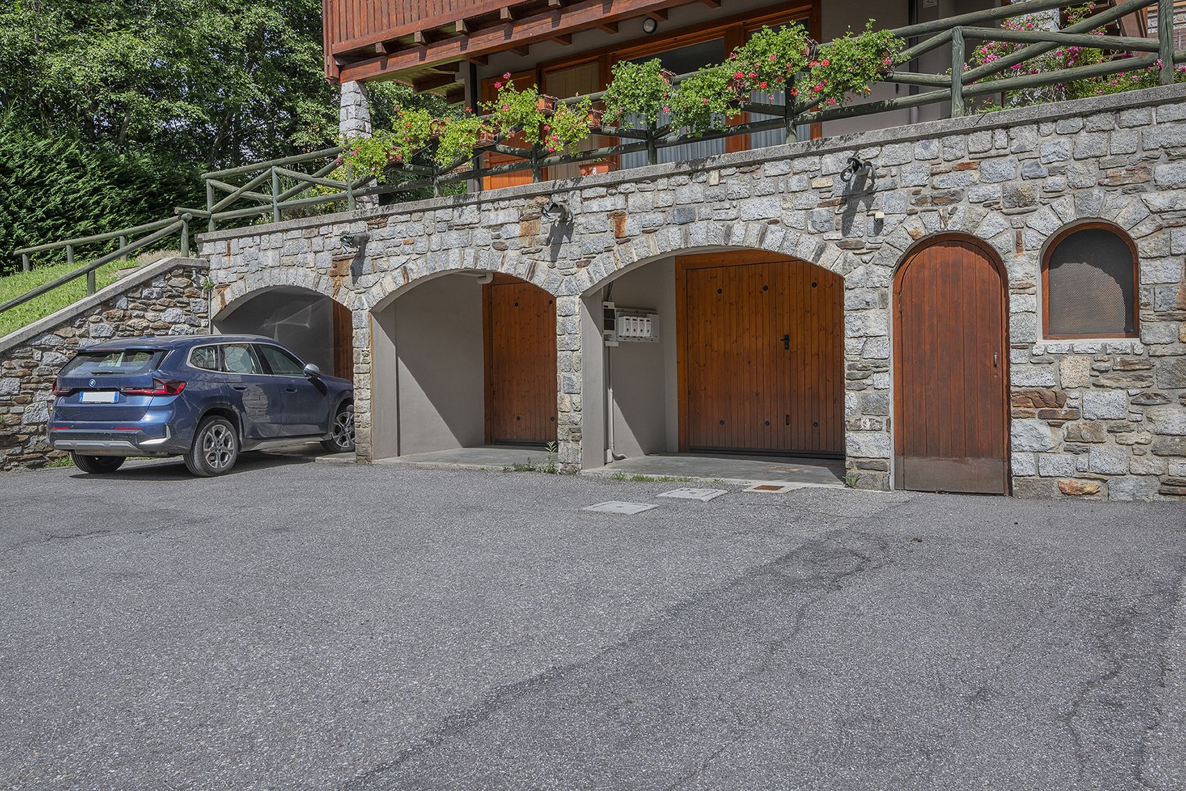 Un edificio in pietra con tre portali ad arco e un'auto parcheggiata davanti.