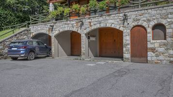 Un edificio in pietra con tre portali ad arco e un'auto parcheggiata davanti.