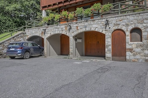 Un edificio in pietra con tre portali ad arco e un'auto parcheggiata davanti.