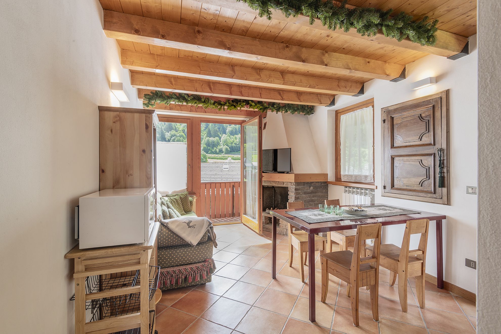 Un ambiente accogliente con soffitto in legno, camino, tavolo da pranzo e divano.