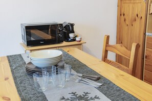 A dining table with a microwave, a coffee maker, bowls, glasses, and cutlery. - La Casa di Bud - AffittiPontediLegno (Temù)