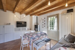A dining area with a table set for two, a television on the wall, and a window with curtains. - AffittiPontediLegno - Sguardo sulle cime (Ponte di legno)
