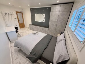 A modern bedroom with a bed, bedside table, and a large mirror. - Modern, Luxury Stay with Free Parking for 3 car's easy access to central London (Potters Bar)