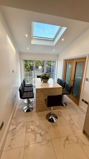 A modern kitchen with a skylight, two bar stools, a marble countertop, and a large window. - Modern, Luxury Stay with Free Parking for 3 car's easy access to central London (Potters Bar)