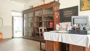 Una habitación con un armario de madera, un escritorio con papeles, una computadora y un extintor.