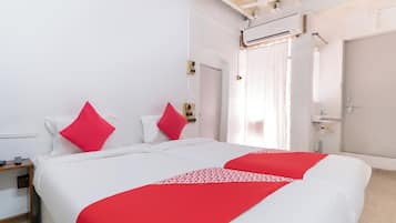 Habitación de hotel con dos camas, una mesita de noche, un espejo, una ventana con cortinas y un ventilador de techo.