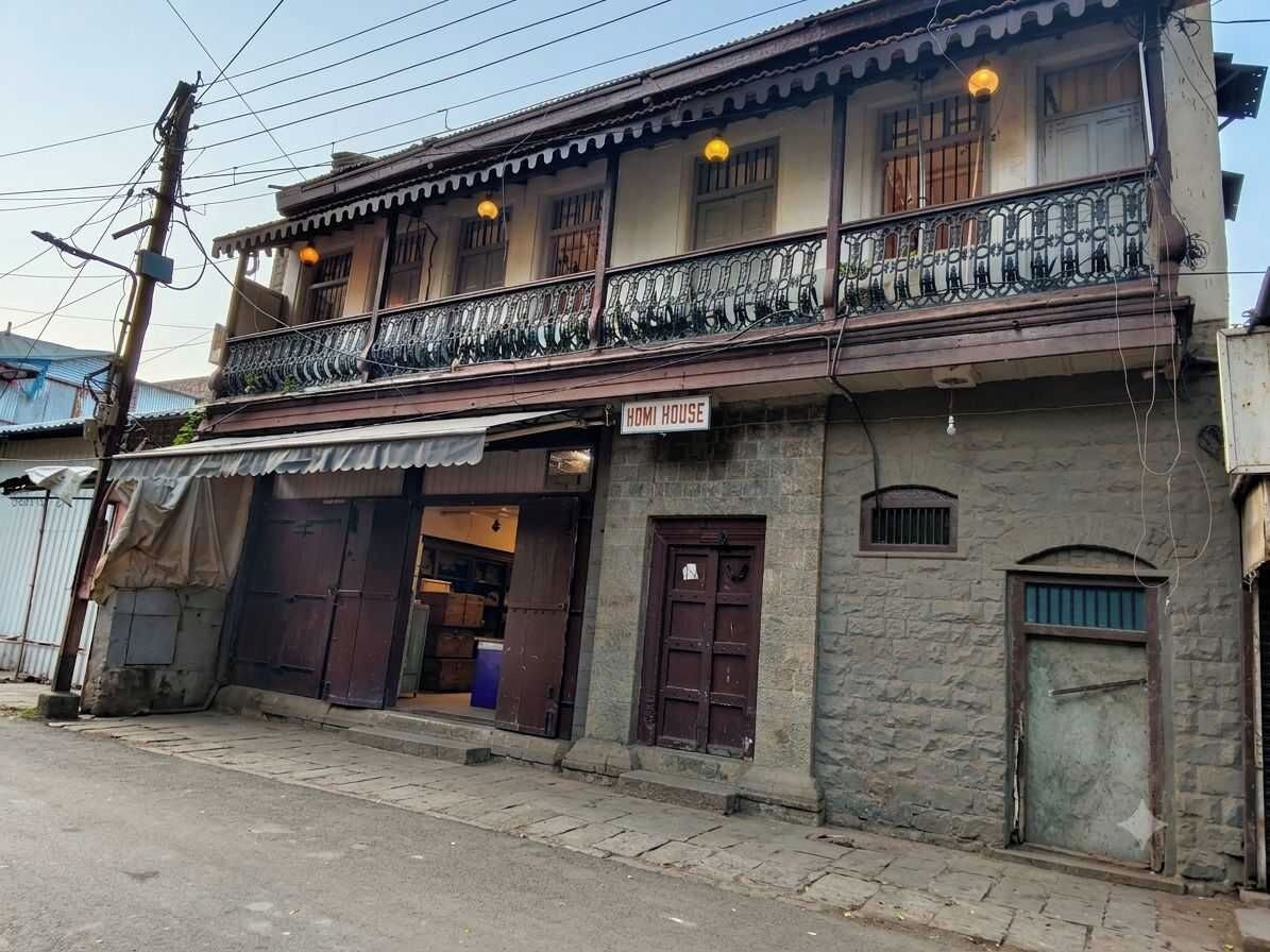 A two-story building with a balcony, a sign reading 'HOMI HOUSE,' and a visible entrance.