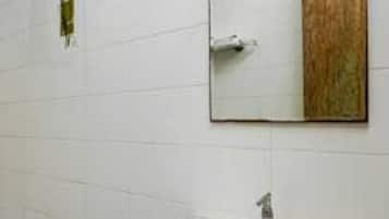 Un baño con un lavamanos blanco, un espejo y un perchero para toallas.