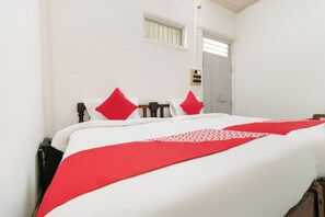 A bed with white bedding and red accents, a wooden headboard, a bedside table with a lamp, and a door with a window above it. - Hotel O Bhuikot Fort Solapur (Solapur)