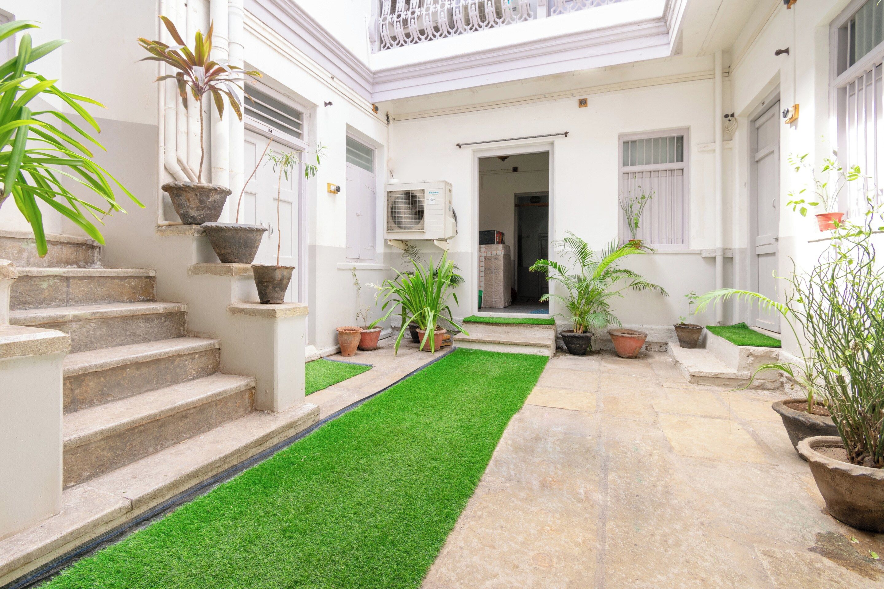 Un patio con un sendero central, escalones que llevan a una puerta y plantas en macetas.