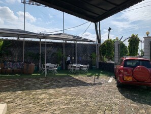 Un espace extérieur aménagé en terrasse, avec un coin salon abrité, des tables et des chaises.