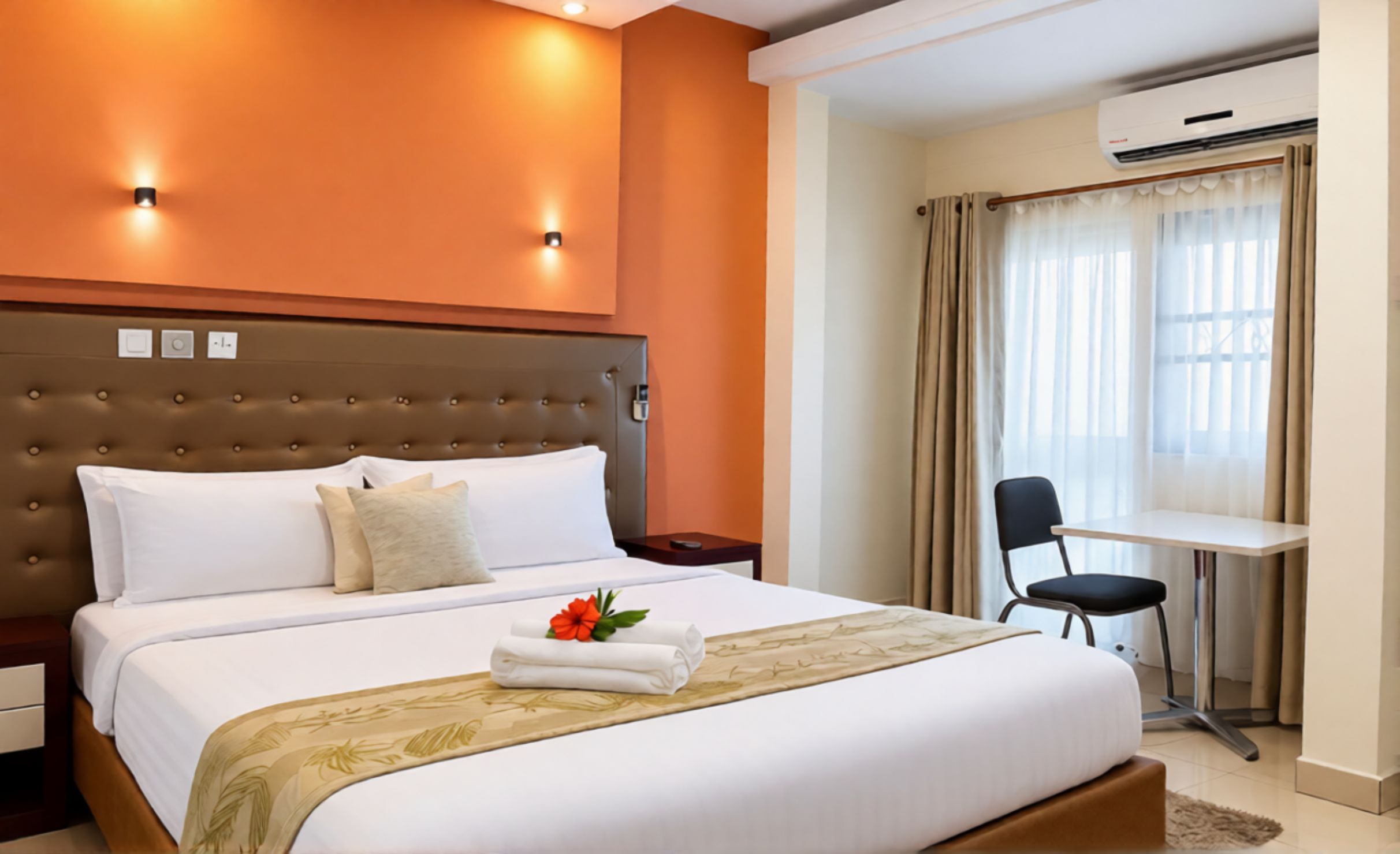 A hotel room with a large bed, a bedside table, a desk, and a chair.