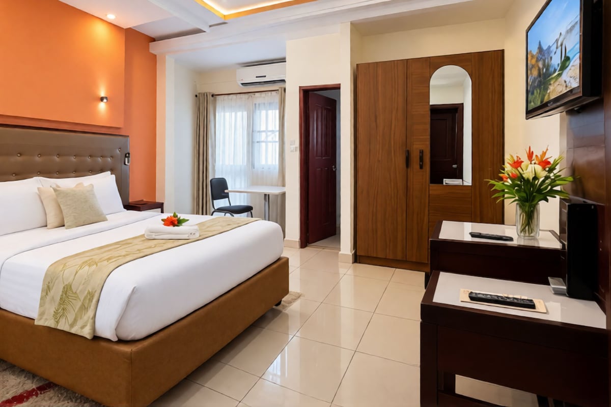 Une chambre d’hôtel avec un grand lit, un bureau, une télévision et une armoire.