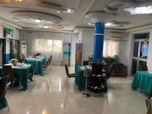 A dining area with tables set for a meal, a decorative column, and a view of the outdoors.