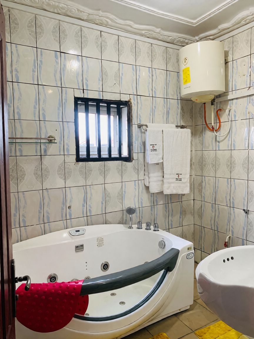 A bathroom with a bathtub, a toilet, a towel rack with towels, and a window.
