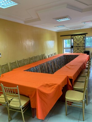 A conference room with a long table, chairs, and a decorative window view. - Hotel Omnisport Limbe (Limbe)