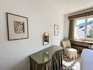 A hotel room with a bed, a desk, a chair, and a window with curtains. - Fullun 14 by Interhome (St. Moritz)