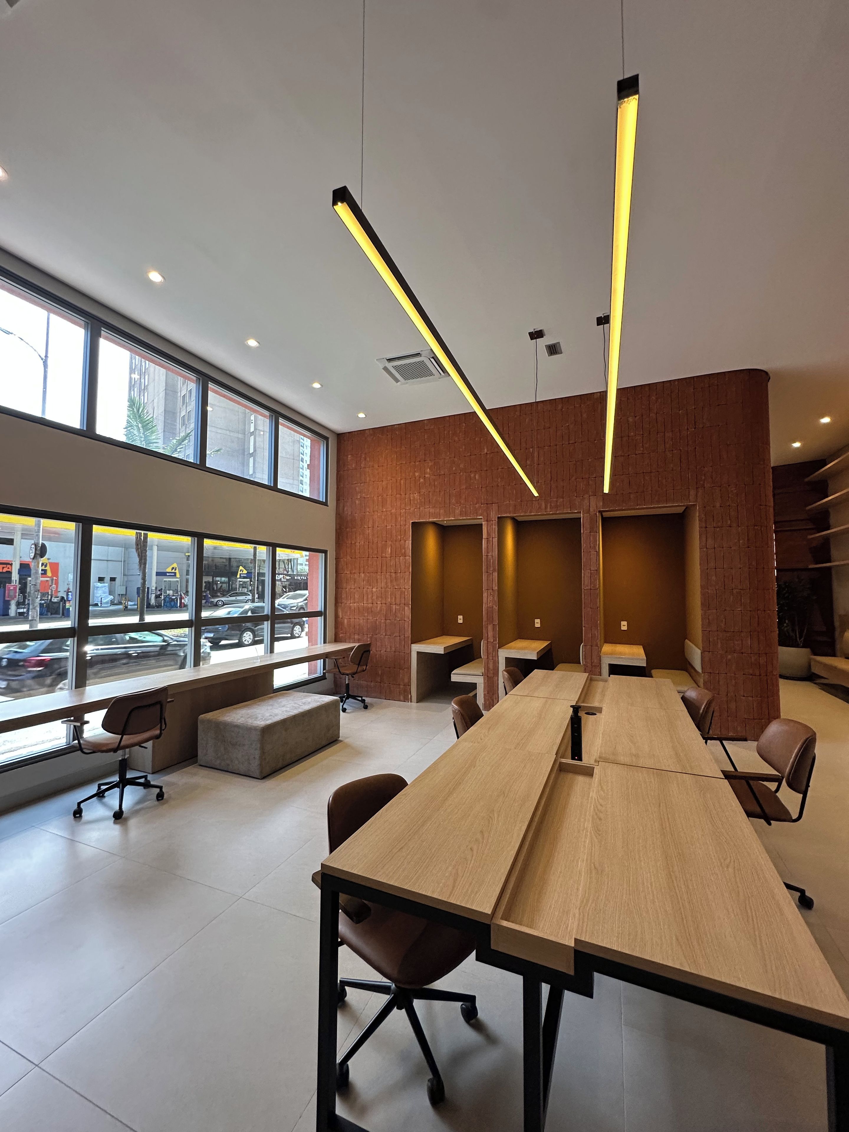 A modern conference room with a long table, chairs, and a view of the street through large windows.
