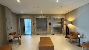 A lobby with marble walls, two elevators, seating area, and a reception desk.