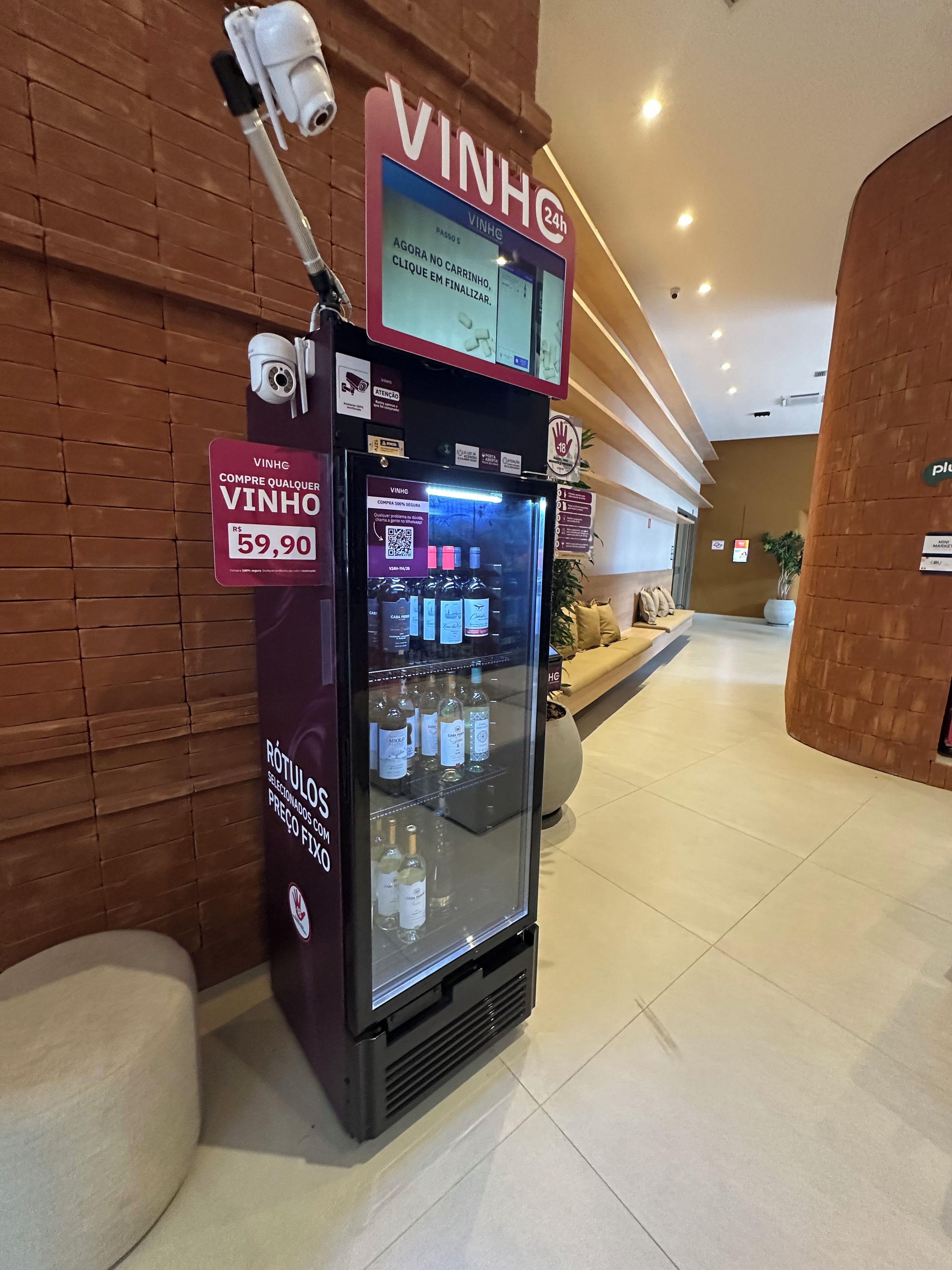 A vending machine with a sign indicating a price of 59.90, located in a lobby with a brick wall and a seating area in the background.