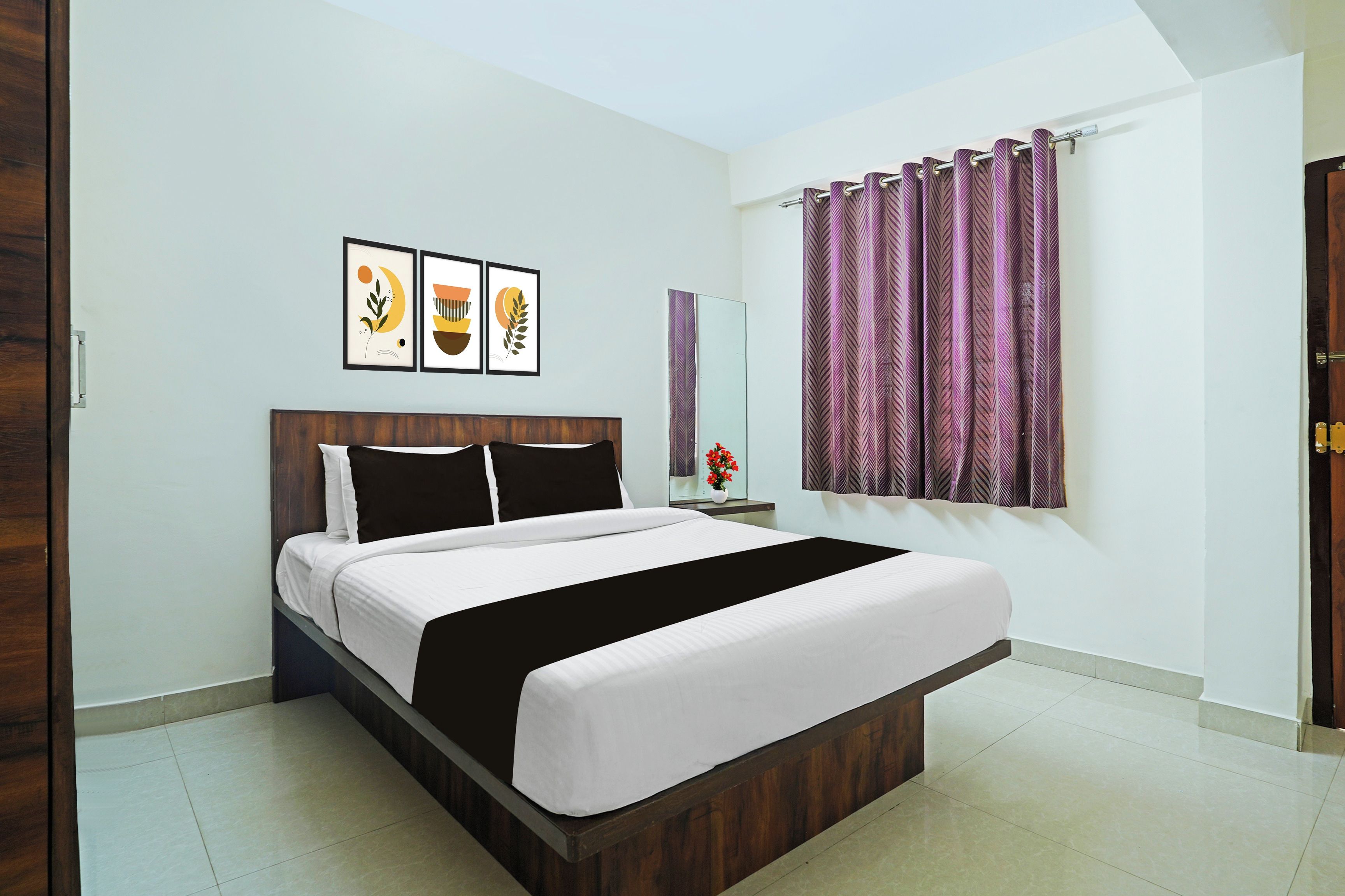 A bedroom with a bed, a nightstand, a mirror, and a window with curtains.