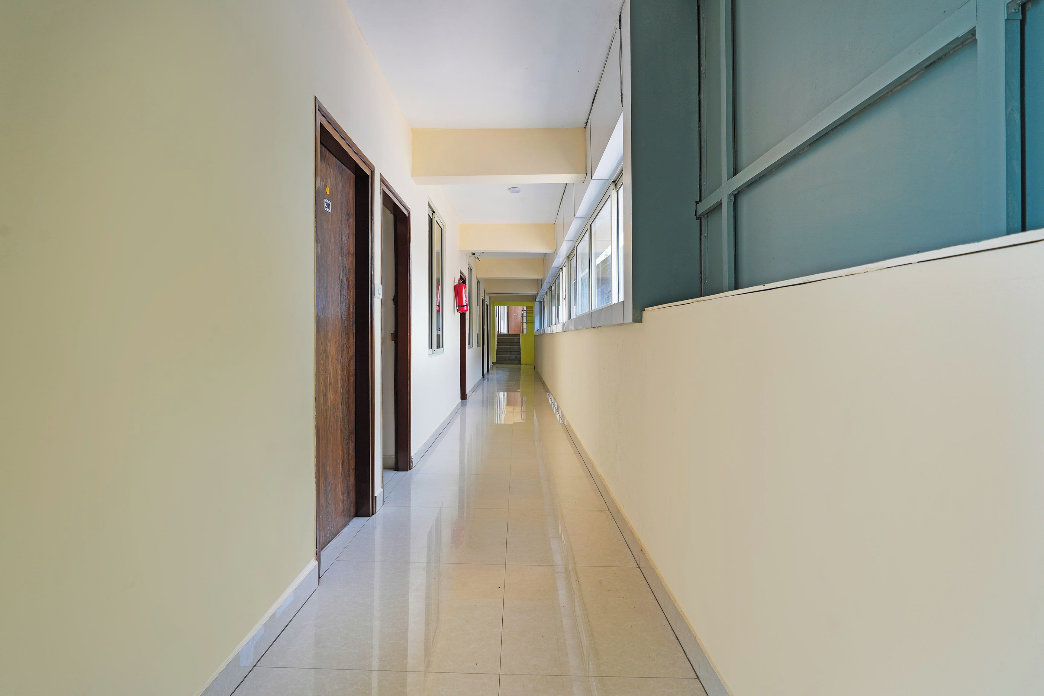 A long, narrow hallway with doors on one side and windows on the other.
