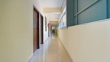 A long, narrow hallway with doors on one side and windows on the other.