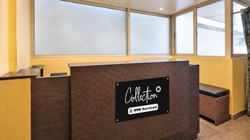 A reception desk with a 'Collection' sign, large windows, and a view of the outside.